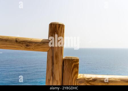 Cette image capture une vue rapprochée d'une balustrade en bois avec l'océan en arrière-plan. Banque D'Images