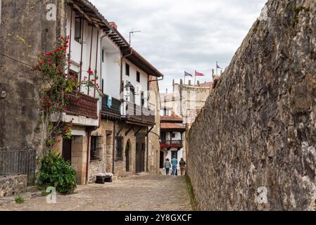 Touristes sur une rue pavée entourée de maisons anciennes et d'un mur de pierre dans la petite ville médiévale Santillana del Mar, région de Cantabrie en Nor Banque D'Images