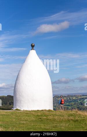 Homme marchant à dos vers White Nancy, un homme a fait un point de repère sur le sentier Gritstone au sommet de Kerridge Hill, surplombant Bollington, Cheshire Banque D'Images