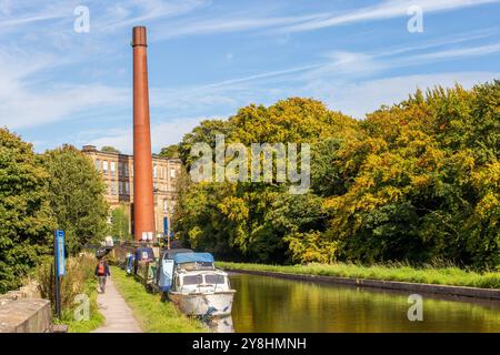 Bateaux amarrés sur le canal Macclesfield à Bollington près de Macclesfield Cheshire avec l'ancienne usine de coton Clarence Mill en vue Banque D'Images