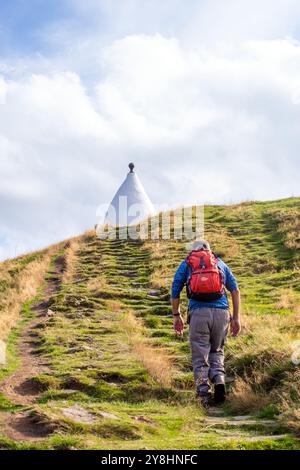 Homme marchant à dos vers White Nancy, un homme a fait un point de repère sur le sentier Gritstone au sommet de Kerridge Hill, surplombant Bollington, Cheshire Banque D'Images