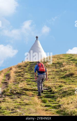 Homme marchant à dos vers White Nancy, un homme a fait un point de repère sur le sentier Gritstone au sommet de Kerridge Hill, surplombant Bollington, Cheshire Banque D'Images