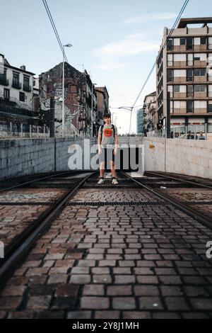 Homme debout posant entre les lignes de tramway à Porto, Portugal Banque D'Images