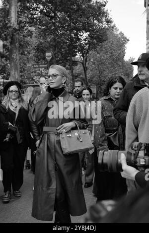 Caro Daur portant une veste-manteau longue en cuir rouge/marron/bordeaux et un pull à col tortue noir et des lunettes de soleil chez Hermès Paris Fashion week SS25 Banque D'Images