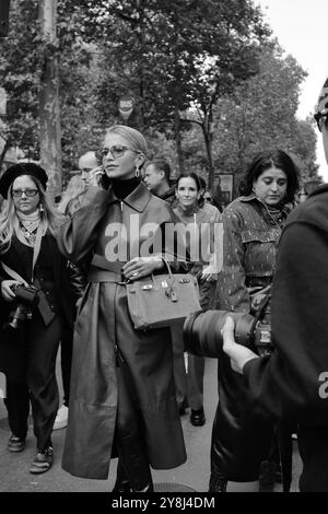 Caro Daur portant une veste-manteau longue en cuir rouge/marron/bordeaux et un pull à col tortue noir et des lunettes de soleil chez Hermès Paris Fashion week SS25 Banque D'Images