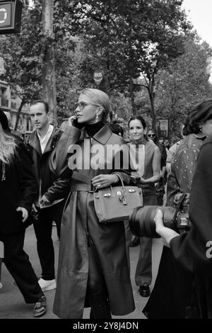 Caro Daur portant une veste-manteau longue en cuir rouge/marron/bordeaux et un pull à col tortue noir et des lunettes de soleil chez Hermès Paris Fashion week SS25 Banque D'Images