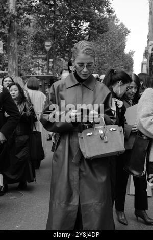 Caro Daur portant une veste-manteau longue en cuir rouge/marron/bordeaux et un pull à col tortue noir et des lunettes de soleil chez Hermès Paris Fashion week SS25 Banque D'Images