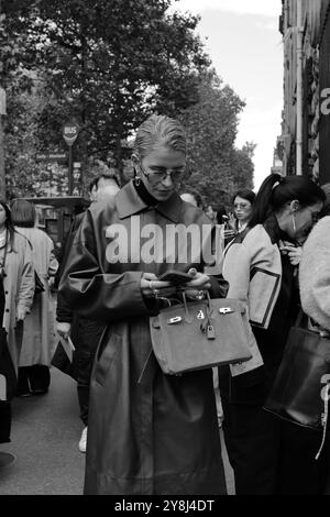 Caro Daur portant une veste-manteau longue en cuir rouge/marron/bordeaux et un pull à col tortue noir et des lunettes de soleil chez Hermès Paris Fashion week SS25 Banque D'Images