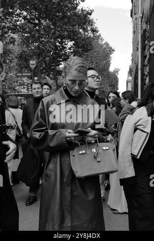 Caro Daur portant une veste-manteau longue en cuir rouge/marron/bordeaux et un pull à col tortue noir et des lunettes de soleil chez Hermès Paris Fashion week SS25 Banque D'Images