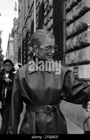 Caro Daur portant une veste-manteau longue en cuir rouge/marron/bordeaux et un pull à col tortue noir et des lunettes de soleil chez Hermès Paris Fashion week SS25 Banque D'Images