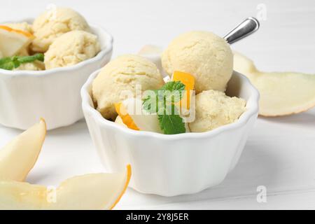 Boules de sorbet de melon à la menthe et aux fruits frais dans des bols sur une table en bois blanc, gros plan Banque D'Images