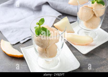 Boules de sorbet de melon à la menthe dans des bols à dessert en verre et des fruits frais sur la table grise, gros plan Banque D'Images