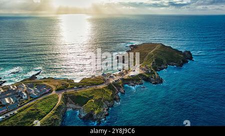 Vue aérienne d'un paysage côtier avec une péninsule s'étendant dans l'océan. Le soleil se couche, projetant une lueur dorée sur l'eau. Petit hou Banque D'Images