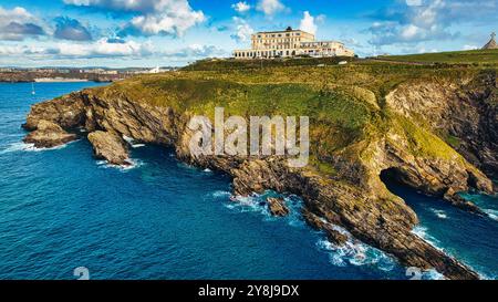 Une vue panoramique sur un paysage côtier avec un grand hôtel perché sur une falaise surplombant l'océan. Le rivage rocheux est visible avec des vagues qui s'écrasent Banque D'Images