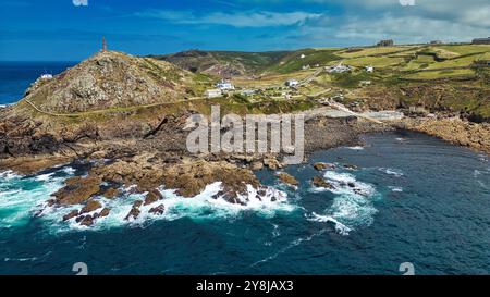 Un paysage côtier pittoresque avec des rivages rocheux, des collines ondulantes et un phare sur une colline. Les vagues de l'océan s'écrasent contre les rochers, avec un clair Banque D'Images