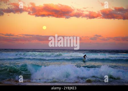 Surfez sur Bondi Beach sydney à la fin de l'hiver 2024. L'image montre un coucher de soleil et une lune levante au-dessus de la mer bleue Banque D'Images