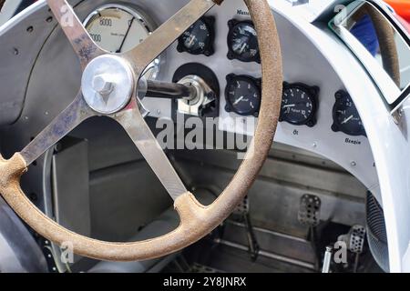 Gros plan d'un volant en cuir avec vue sur l'ancien tableau de bord d'une voiture de course vintage. Banque D'Images