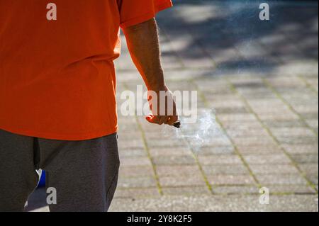 Un homme dans une chemise orange tient un bâton de sauge brûlant lors d'un événement de vérité et réconciliation. La sauge est utilisée dans la culture des Premières Nations pour faire de la boue. Banque D'Images