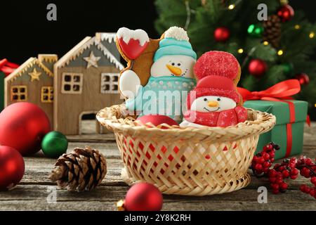 Délicieux biscuits en forme de bonhommes de neige et décor de Noël sur table en bois Banque D'Images