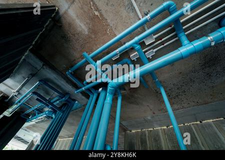 Un tuyau bleu vif attaché à un mur de béton solide Banque D'Images