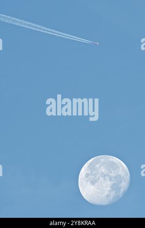 Avion de transport fait la ligne de trace de chemtrails sur le ciel bleu et volant au-dessus de la lune. Théorie du complot. Banque D'Images