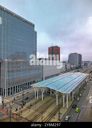 Station de tramway moderne à Łódź, en Pologne, avec des tramways vibrants et un toit en auvent coloré dans un cadre urbain animé par une journée nuageuse Banque D'Images