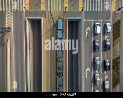 Vue aérienne d'un tramway unique voyageant sur un pont au-dessus d'une route à Łódź, Pologne, capturée directement au-dessus, avec des motifs symétriques de rails et R. Banque D'Images