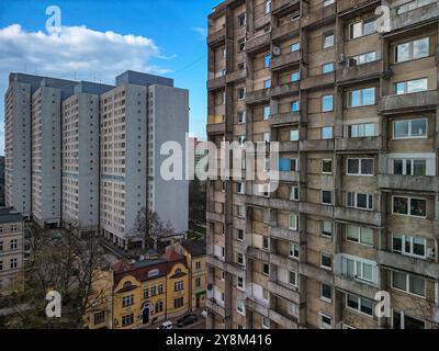 Titre : architecture résidentielle contrastée à Łódź : gratte-ciel moderne à côté de bâtiments plus anciens sous un ciel bleu clair Banque D'Images