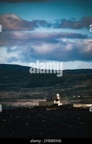 Scène côtière avec collines. Un paysage côtier présente des collines ondulantes et un phare lointain. Banque D'Images