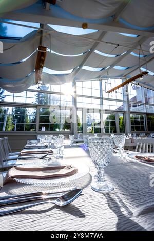 Verre de cristal sur la table dans une salle de banquet lumineuse aux parois de verre. Photo prise pendant la journée, avec la lumière du soleil. Banque D'Images