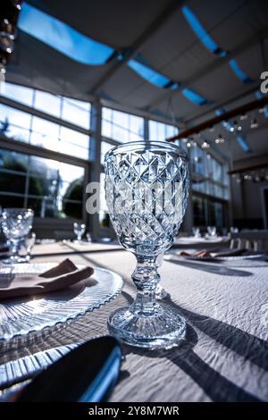 Verre de cristal sur la table dans une salle de banquet lumineuse aux parois de verre. Photo prise pendant la journée, avec la lumière du soleil. Banque D'Images