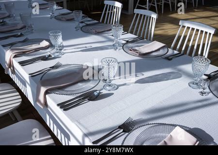 Verre de cristal sur la table dans une salle de banquet lumineuse aux parois de verre. Photo prise pendant la journée, avec la lumière du soleil. Banque D'Images