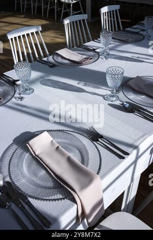 Verre de cristal sur la table dans une salle de banquet lumineuse aux parois de verre. Photo prise pendant la journée, avec la lumière du soleil. Banque D'Images