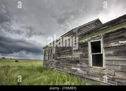Ferme abandonnée avec les nuages de tempête dans les Prairies canadiennes Banque D'Images