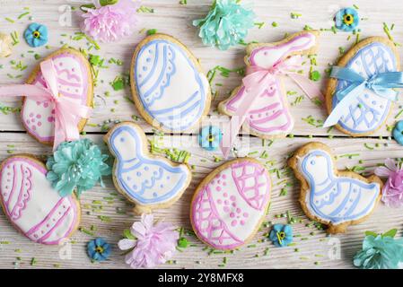 Biscuits givrés de Pâques en forme de poule d'oeuf et de lapin sur fond de table en bois blanc avec des saupoudrages de sucre. Maquette horizontale posée à plat Banque D'Images