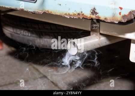 Un tuyau d'échappement fumant d'une vieille voiture rouillée montrant les émotions enfumées provenant du moteur des voitures Banque D'Images