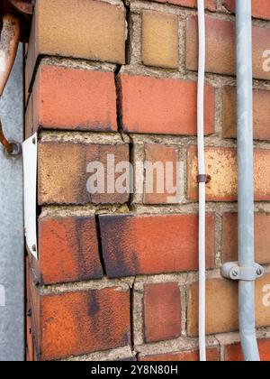 Gros plan d'une grande fissure dans un mur de briques indiquant le mouvement du bâtiment. Banque D'Images