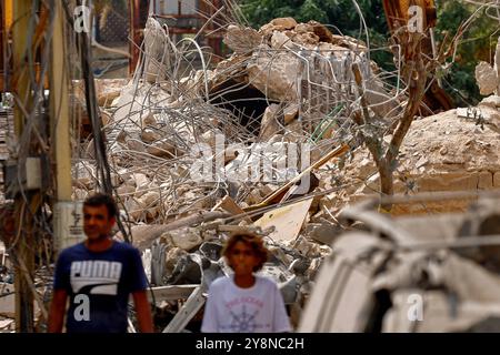 Jiyeh, Liban. 06 octobre 2024. Des résidents libanais s'éloignent des décombres d'un bâtiment aplati, ciblé par un raid aérien israélien, dans le village de Jiyeh, dans le sud du pays. Crédit : Stringer/dpa/Alamy Live News Banque D'Images