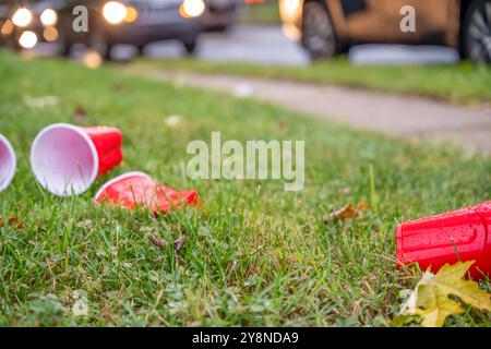 Tasses en plastique rouge écrasées et jetées après une fête universitaire Banque D'Images