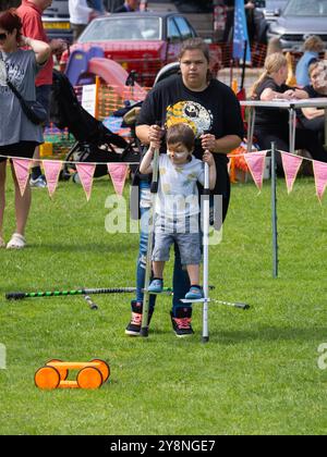 Un jeune enfant apprend à marcher sur pilotis lors d'un atelier sur les compétences du cirque, Bude, Cornwall, Royaume-Uni Banque D'Images