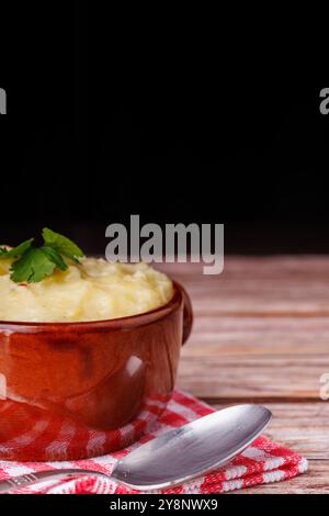 Offrez-vous un bol de purée de pommes de terre avec une cuillère et une serviette rouge à carreaux, sur fond d'une charmante table en bois Banque D'Images