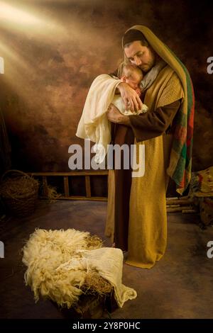 Saint Joseph tenant l'enfant Jésus pendant une scène de nativité en direct Banque D'Images