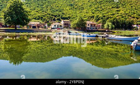 Mikrolimni, Grèce - juillet 29 2023 : le paisible village de Mikrolimni sur les rives du lac de Prespa, avec de petits bateaux de pêche amarrés le long du front de mer, Banque D'Images