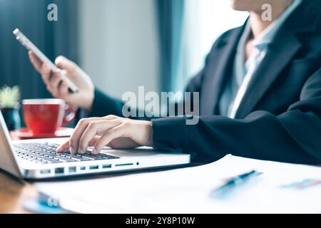 Femme est assise à table, utilisant son téléphone portable pour naviguer sur les médias sociaux et mener des affaires grâce aux dernières technologies dans le cyberespace. médias sociaux, table Banque D'Images