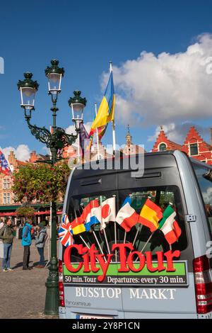 Belgique, Flandre, Bruges, place du marché, Grote Markt, drapeaux à l'arrière du bus City Tour Banque D'Images