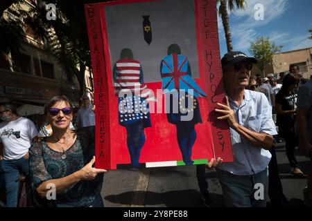 Malaga, Espagne. 06 octobre 2024. Les manifestants portent une grande pancarte dénonçant la situation en Palestine lors d’une manifestation mondiale contre le génocide en Palestine suite à l’escalade du conflit au moyen-Orient. La veille de l’anniversaire des attentats du 7 octobre et du début de la guerre entre Israël et le Hamas, des milliers de personnes descendent dans les rues de la ville de Malaga en solidarité avec le Liban et la Palestine pour exiger la fin du commerce des armes avec Israël et de l’occupation militaire israélienne en Palestine. Crédit : SOPA images Limited/Alamy Live News Banque D'Images