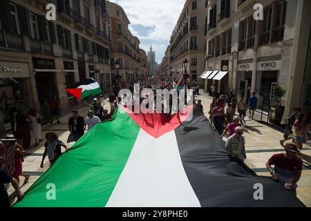 Malaga, Espagne. 06 octobre 2024. Les manifestants tiennent un grand drapeau palestinien lors d'une manifestation mondiale contre le génocide en Palestine suite à l'escalade du conflit au moyen-Orient. La veille de l’anniversaire des attentats du 7 octobre et du début de la guerre entre Israël et le Hamas, des milliers de personnes descendent dans les rues de la ville de Malaga en solidarité avec le Liban et la Palestine pour exiger la fin du commerce des armes avec Israël et de l’occupation militaire israélienne en Palestine. (Photo de Jesus Merida/SOPA images/SIPA USA) crédit : SIPA USA/Alamy Live News Banque D'Images