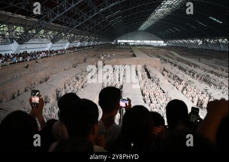 06 octobre 2024, Chine, Xi'an : les visiteurs photographient les guerriers d'argile de l'armée de terre cuite sur le site du mausolée de Qin Shi Huangdi, le premier empereur de Chine, dans la salle de fouilles numéro un. Photo : Johannes Neudecker/dpa Banque D'Images