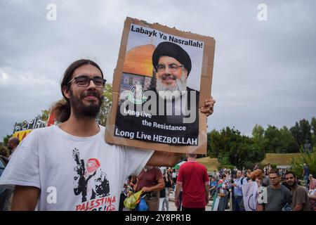 Athènes, Grèce. 5 octobre 2024. Un manifestant tient une pancarte avec le visage de Hassan Nasrallah qui dit, ''Labayk ya Nasrallah! Vive la résistance, vive le Hezbollah.'' Des centaines de manifestants ont défilé dans les rues d’Athènes contre les guerres et en solidarité avec le Liban et la Palestine. Crédit : Dimitris Aspiotis/Alamy Banque D'Images