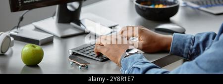 En-tête du site Web tir des mains d'un ingénieur INFORMATIQUE afro-américain tapant sur le clavier, écrivant le code dans le bureau avec la pomme verte et le doigt sur le bureau de travail Banque D'Images